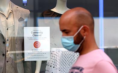 man walking past closed store wearing a face mask during coronavirus pandemic