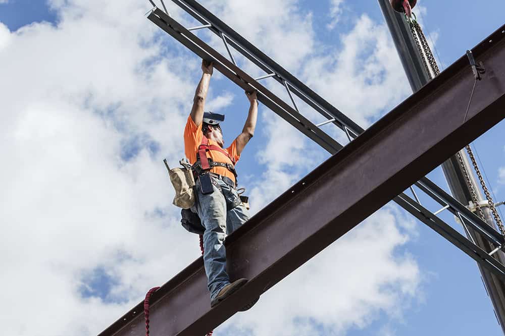 Ironworker at construction site installing roof joist