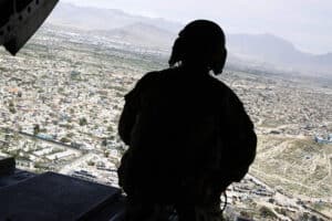 A U.S. soldier mans a gun at the back gate aboard a helicopter