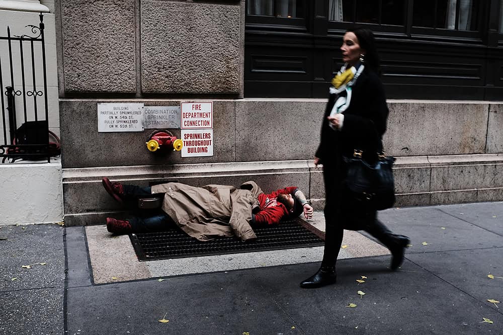A woman walks by a homeless man along a Manhattan street