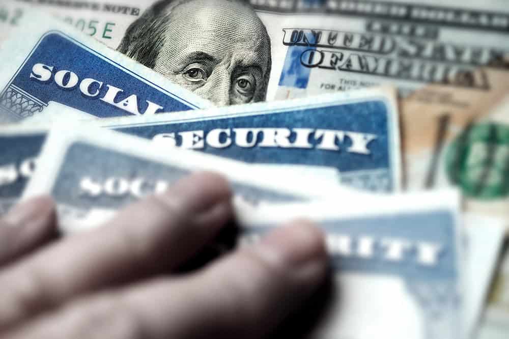 Image of Social Security cards on top of hundred dollar bills.
