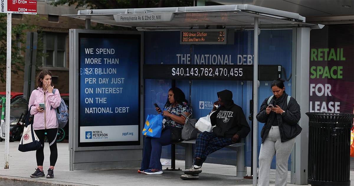 A view of a bus shelter where an electronic billboard and a poster display the current U.S. National debt per person and as a nation in Washington, DC.